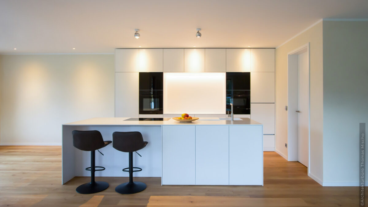 Moderne, weiße Küche mit Barhocken und Bolzbodenbelag