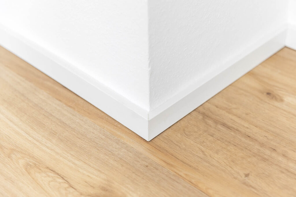 Bodenbelagsarbeiten Detailansicht Ecke Vinylboden Eiche weiße Fußleisten Ewering