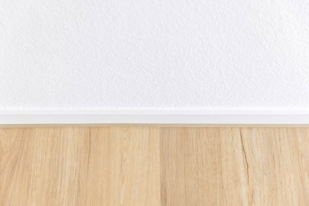 Bodenbelagsarbeiten Detailansicht Vinylboden Eiche weiße Fußleisten Ewering