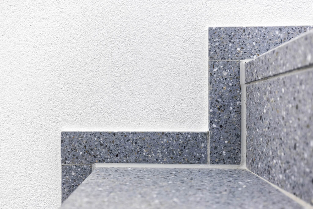 Treppenhaus Malerarbeiten Detailansicht Putztechnik weiße Wand und Abschluss der Stufe und Wand Ewering