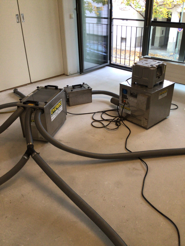 Mehrere Trocknungsgeräte und Schläuche von Ewering stehen in einem leeren Raum zur technischen Trocknung nach einem Wasserschaden.