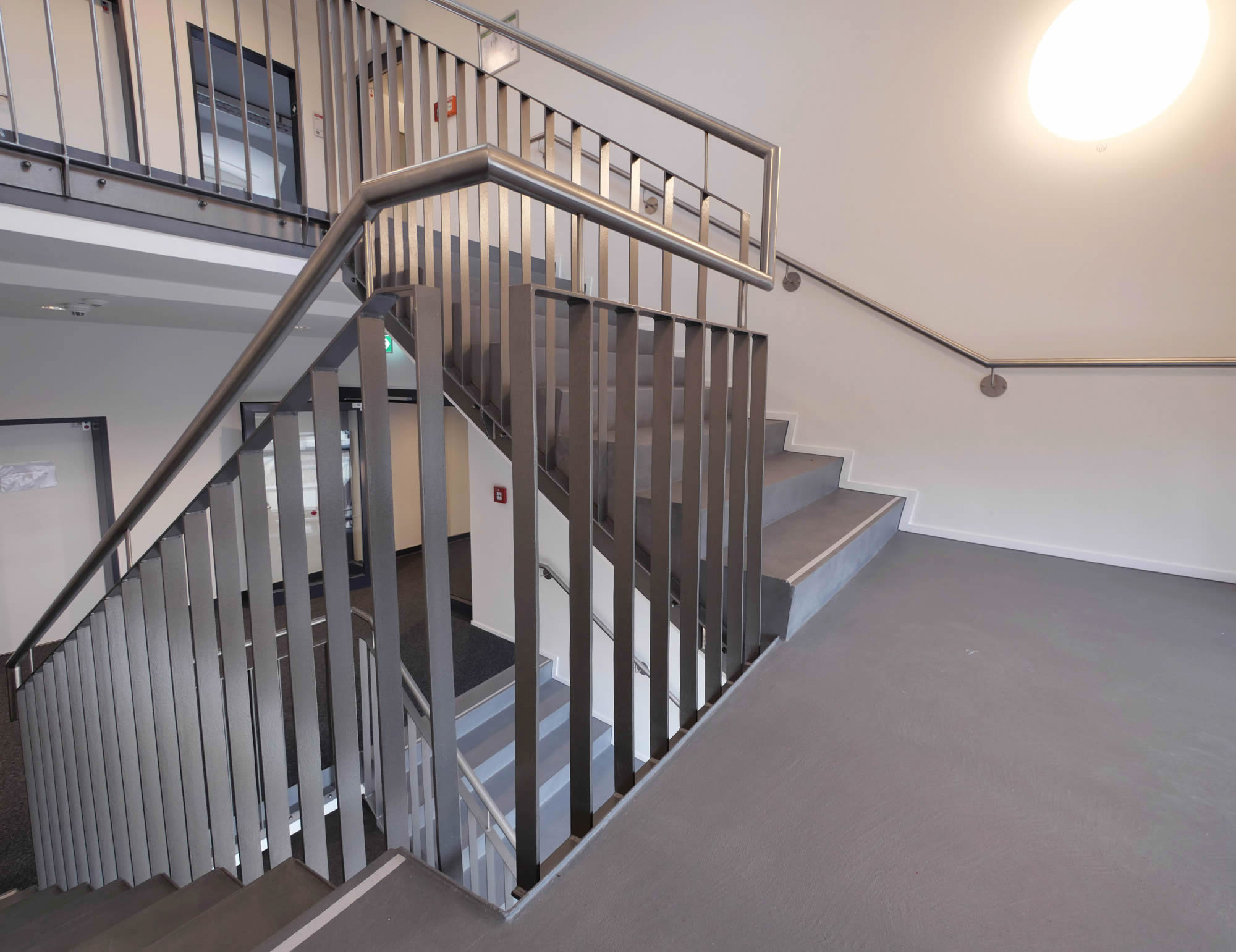 referenz_afa_coesfeld_treppenpodest_metallgelaender_graue_treppenanlage_wandleuchte