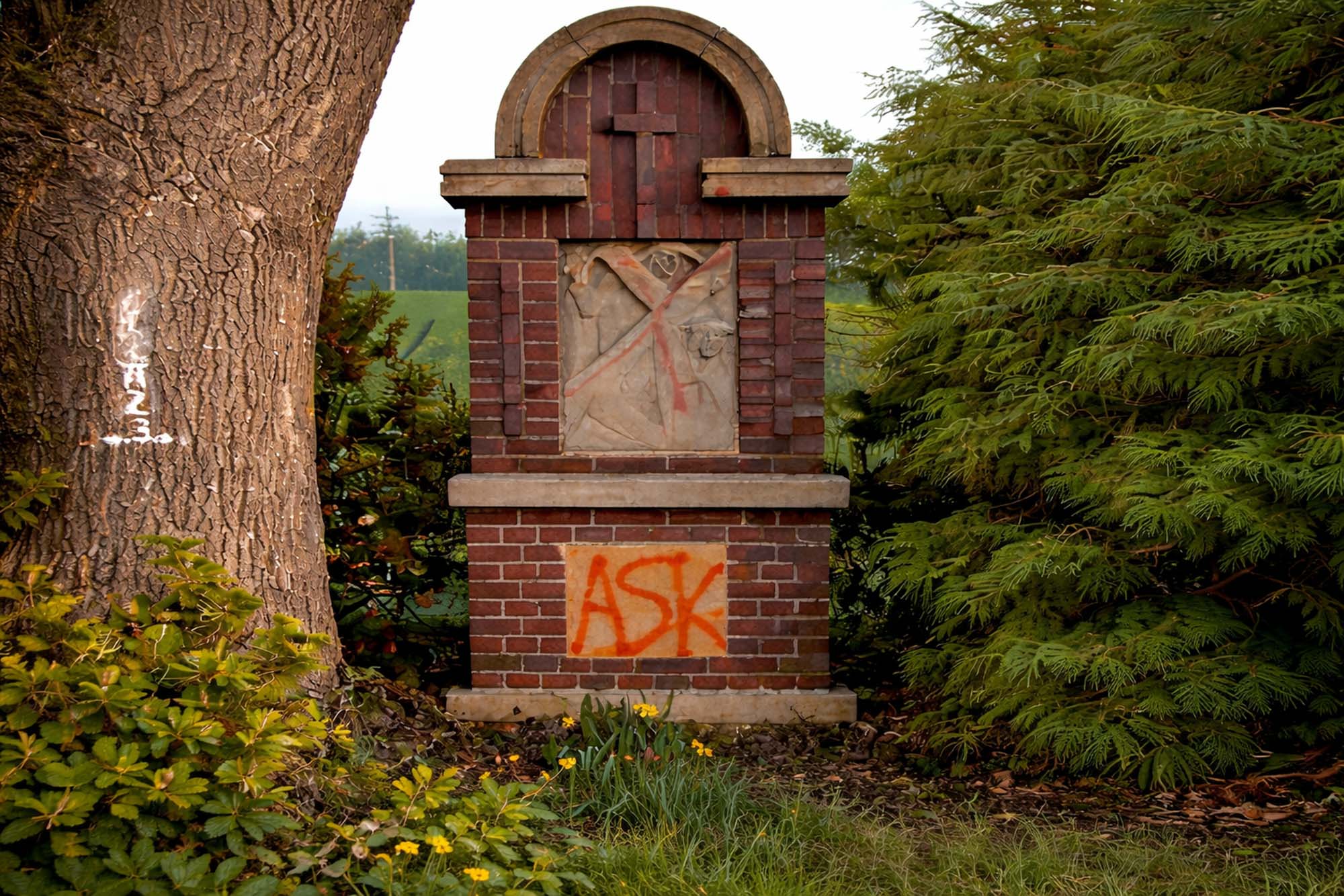 Naturstein- und Mauerwerkselement mit orangefarbenem Graffiti vor der Graffitientfernung