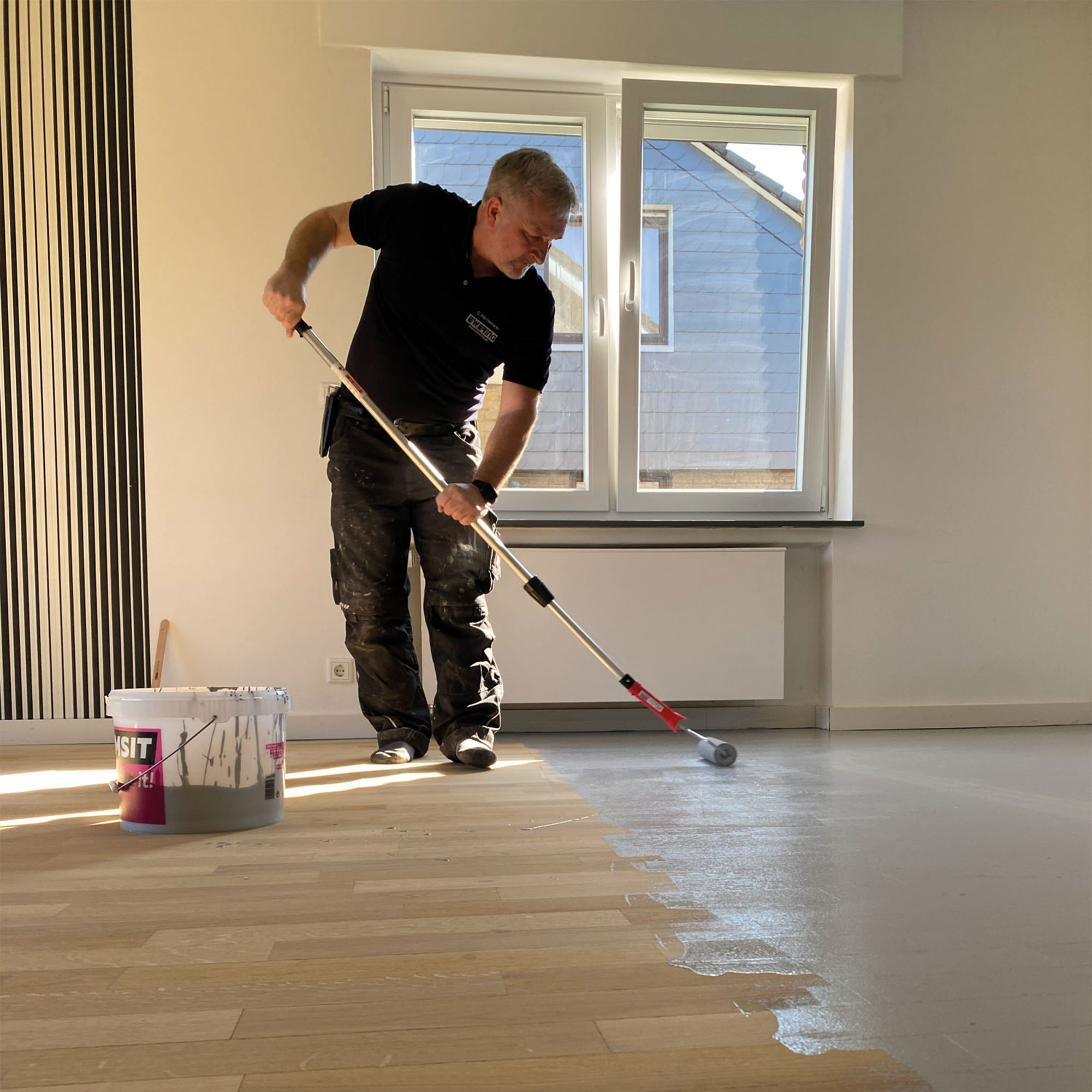 Mitarbeiter behandelt Parkett nach dem Abschleifen